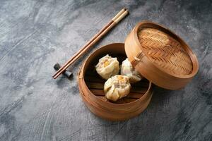 Chinese steamed dumplings or  Dim Sum in bamboo steamer on dark abstract background photo