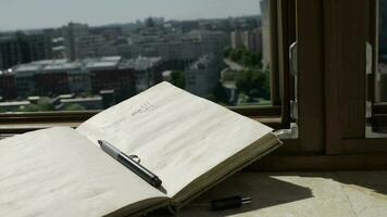 Diary with a pen at marble sill of an open window. Blowing grey transparent curtains video