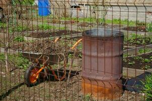 a cart with tops and a barrel for burning garbage. Cleaning on the site photo