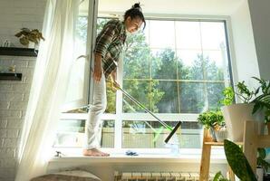 Woman manually washes the window of the house with a rag with spray cleaner and mop inside the interior with white curtains. Restoring order and cleanliness in the spring, cleaning servise photo