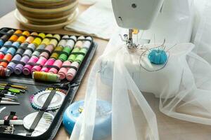 Sewing layout with multicolored spools of thread close-up, needles, electric sewing machine. Filling the thread into the sewing needle, adjusting the tension. hobby, home business photo