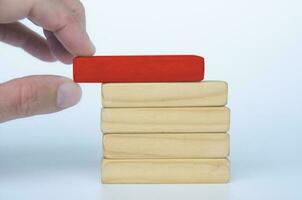 Hand putting red wooden block on top of other wooden blocks. Customizable space for text. Copy space photo