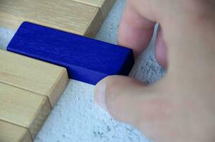 Hand pulling blue wooden block from other wooden block with customizable space for text. Copy space. photo