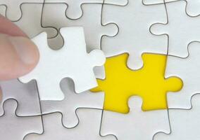 Hand holding separated jigsaw puzzle with customizable space for text. Copy space with yellow background photo