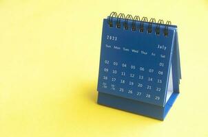 July 2023 blue desk calendar on yellow cover background with customizable space for text. Copy space and calendar concept photo