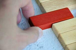 Hand pulling red wooden block from other wooden block with customizable space for text. Copy space. photo