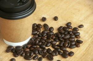 Takeaway coffee cup surrounded with coffee beans with customizable space for text or ideas. Copy space and coffee concept photo