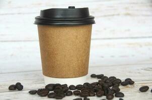 Takeaway coffee cup surrounded with coffee beans with customizable space for text or ideas. Copy space. photo