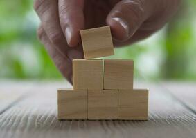 Hand placing wooden cube on top of stacked wooden cube. Copy space. photo