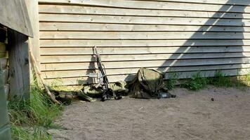 Close up soldiers unattended G-36 gun by his military bag and vest rest by building wall outside video