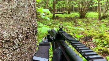 Soldier first person point of view hide behind tree wait prepare for attack or ambush in forest. Military trainings and army exercise in the woods video