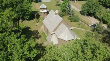 Aerial view Young lithuanians relax on sunday mass by St. Joseph Church in Paluse, Lithuania. Stave Churches in Europe. Old heritage sites. Walls formed by vertical wooden boards. video