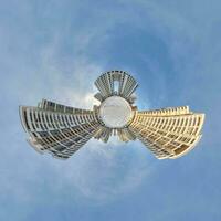 tiny planet in blue sky with clouds in city center near modern skyscrapers in residential complex. Transformation of spherical 360 panorama in abstract aerial view. photo