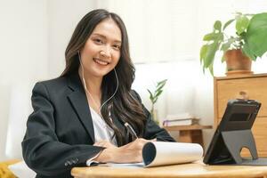 Online communication, asian young woman in formal suit wearing earphones, using tablet having online virtual job interview meeting conversation on video call, distance remote recruitment conference. photo