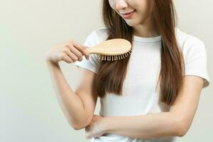 salud pelo cuidado, belleza maquillaje asiático mujer mano en participación cepillo para el pelo y cepillado, peinada su largo Derecho pelo en el Mañana rutina después salón tratamiento, peinado. aislado en blanco antecedentes foto