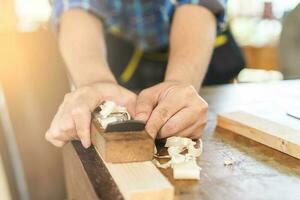 carpintería profesional, asiático joven hombre, masculino carpintero utilizar máquinas o herramienta, virutas escabroso en madera, madera a industrial. carpintería, mueble haciendo, construcción industria. propietario pequeño negocio. foto