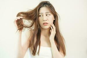 Damaged Hair, frustrated asian young woman, girl hand in holding splitting ends, messy unbrushed dry hair with face shock, long disheveled hair, health care of beauty. Portrait isolated on background. photo