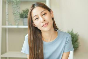 Smiling positive, attractive asian young woman wearing blue t-shirt casual, portrait of beautiful brunette with long hair, feeling happy and relaxing, looking at camera at home, isolated on background photo