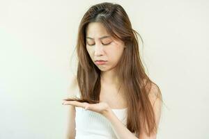 Damaged Hair, frustrated asian young woman, girl hand in holding splitting ends, messy unbrushed dry hair with face shock, long disheveled hair, health care of beauty. Portrait isolated on background. photo