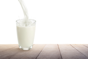 Milk is poured into a glass placed on a wooden floor PNG transparent