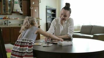 Young mother invites her daughter to play table game at the table video