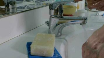 Young lady between 30 and 35 years old is washing her hands with soap in the bathroom. Closeup video