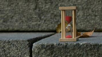 Sand watch in wooden fame on a gray stone. Closeup video