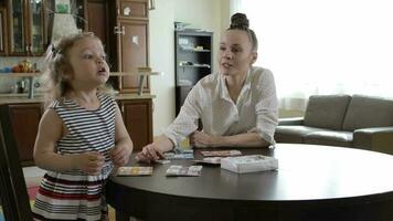 Young mother invites her daughter to play table game at the table video