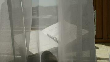 Diary with a pen at marble sill of an open window. Blowing grey transparent curtains video