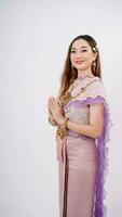 lujo retrato de un hermosa tailandés niña en tradicional tailandés disfraz posando a pagar el respeto con sonriente aislado en blanco antecedentes foto