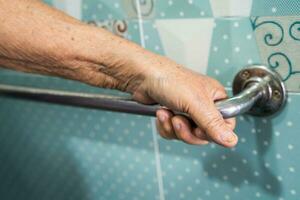 Asian senior woman patient use toilet bathroom handle security in nursing hospital, healthy strong medical concept. photo