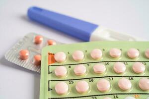 Pregnancy test and birth control pills on calendar, contraception health and medicine. photo