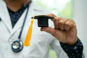 Asian doctor study learn with graduation gap hat in hospital ward, clever bright genius education medicine concept. photo