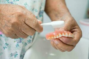 Asian elderly woman patient holding to use denture, healthy strong medical concept. photo