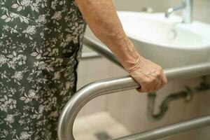 asiático mayor antiguo dama mujer paciente utilizar baño baño encargarse de seguridad en enfermería hospital, sano fuerte médico concepto. foto