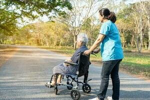cuidador ayuda y cuidado asiático mayor mujer en silla de ruedas a parque con contento en día festivo. foto