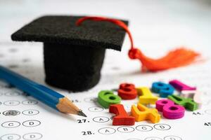 Graduation gap hat and pencil on answer sheet background  Education study testing learning teach photo
