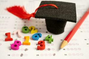 Graduation gap hat and pencil on answer sheet paper, Education study testing learning teach concept. photo