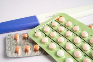 Pregnancy test and birth control pills on calendar, contraception health and medicine. photo