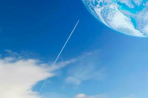 A private jet plane flying with contrail or vapor trails heading to the planet on blue sky photo