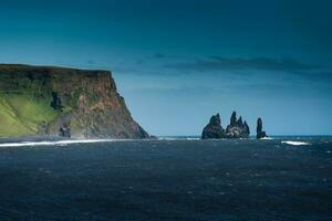 Dramatic moody famous Reynisdrangar rock formation and black Reynisfjara Beach at coastline of Atlantic ocean in Vik, Iceland photo