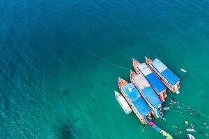 Traditional ferry anchored and tourist snorkeling and enjoying with coral reef in tropical sea photo