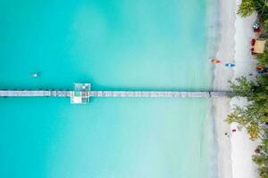 Tourist canoeing by wooden pier in turquoise sea and the beach on summer at tropical island photo