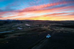 4wd car parked on dirt road among moss lava field in the sunset on Icelandic highlands in summer of Iceland photo