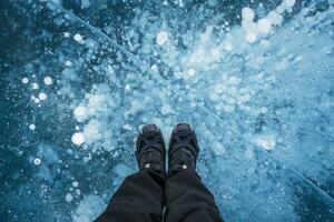 hombre en botas en pie en congelado lago con natural burbuja en invierno foto