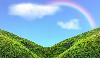 Green mountain slope with rainbow in blue sky photo