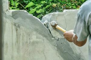 mano de trabajador utilizando martillo imponente y demoler en ladrillo pared a construcción sitio foto