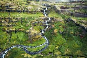 Beautiful Klifbrekkufossar waterfall flowing in Mjoifjordur fjord on summer in Iceland photo