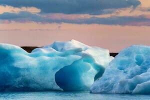 Scenery of Jokulsarlon glacier lagoon with blue iceberg melting and sunset sky on summer photo