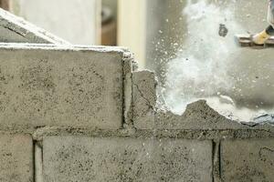 Hand of worker using hammer smashing and demolish on brick wall at construction site photo